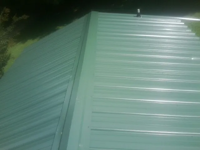 New green metal panels meeting at the ridge of a roof — Flat Roof Repair work by our crew in Moorestown