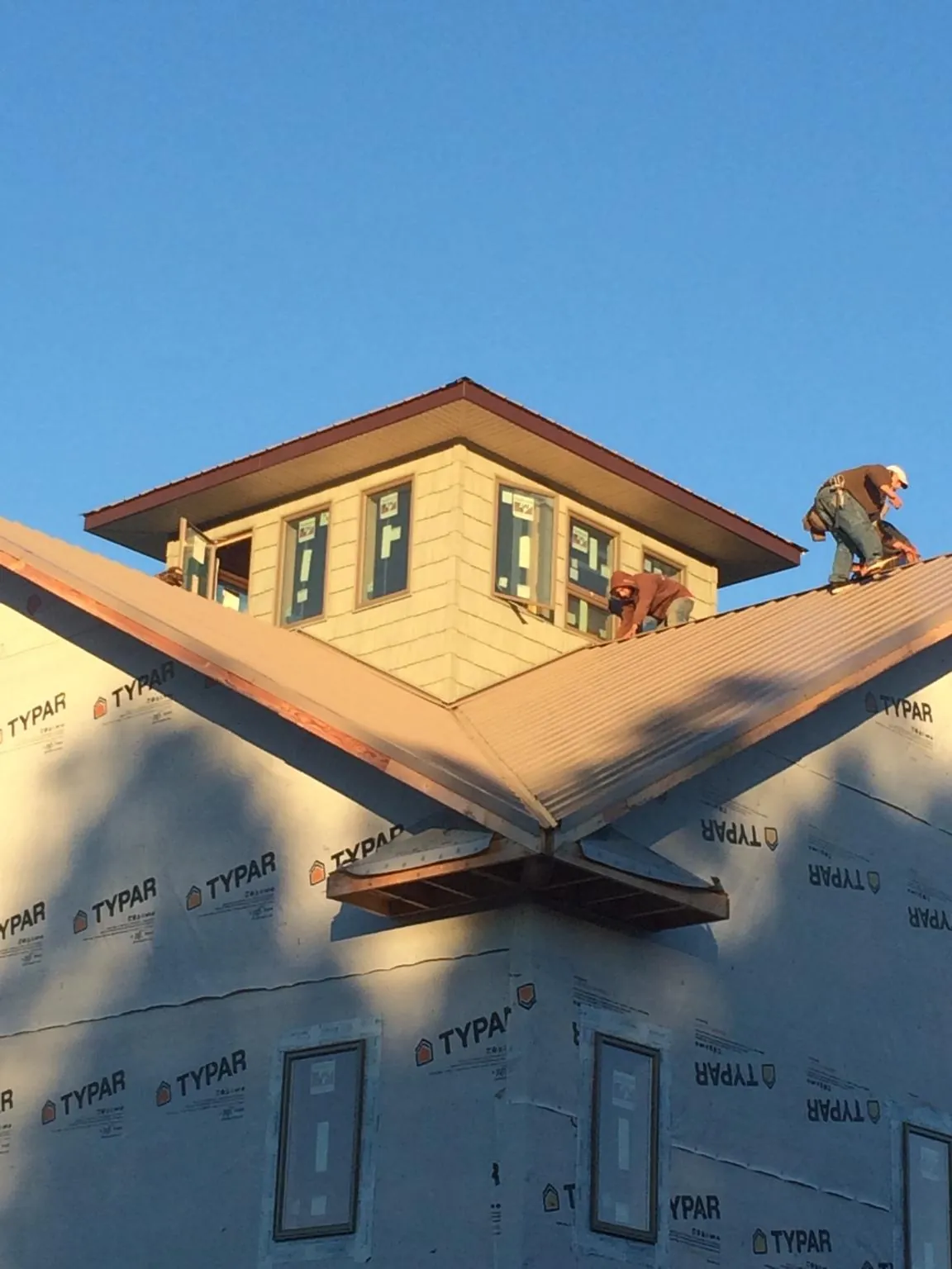 Roofers working around a rooftop cupola on a new metal roof at sunset — Roof Waterproofing in Moorestown by Roofing Brothers